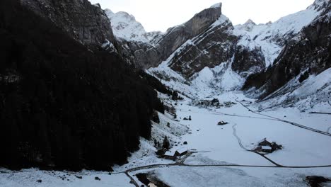 Aerial-flyover-above-Seealpsee-in-Appenzell,-Switzerland-from-the-snow-covered-shores-towards-a-reflection---4k