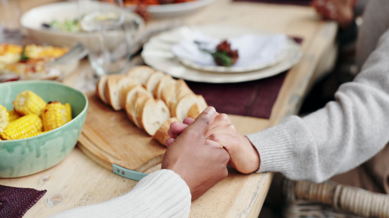 Family holding hands at dinner table