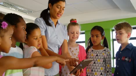 maestra asiática que enseña en una tableta digital en la biblioteca de la escuela 4k