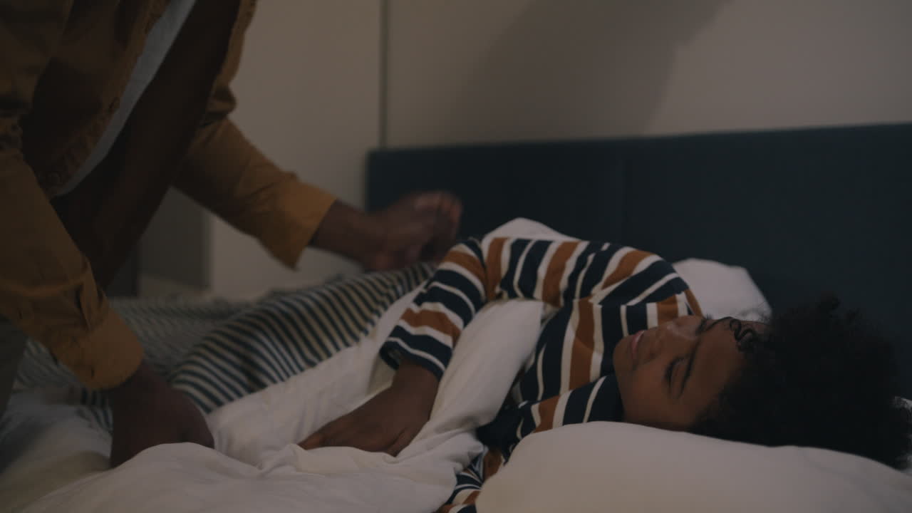 Father tucking his son into bed at night