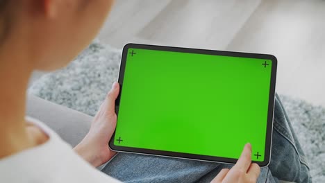 close up de mujer sosteniendo en las manos una tableta digital con pantalla verde para internet en línea, pantalla clave de croma para publicidad.