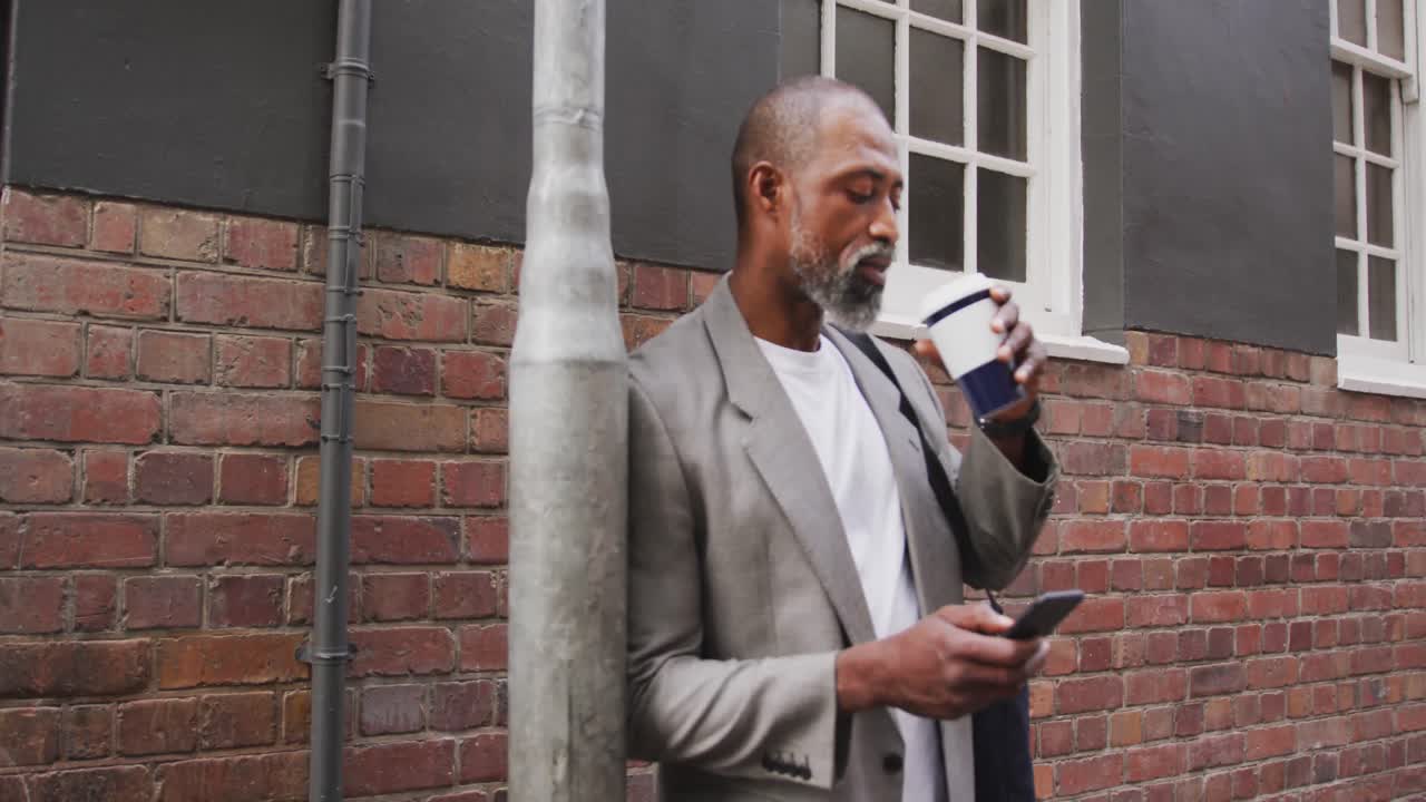 African American man drinking a coffee and using his phone
