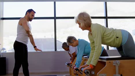 trainer assisting senior women to exercise 4k