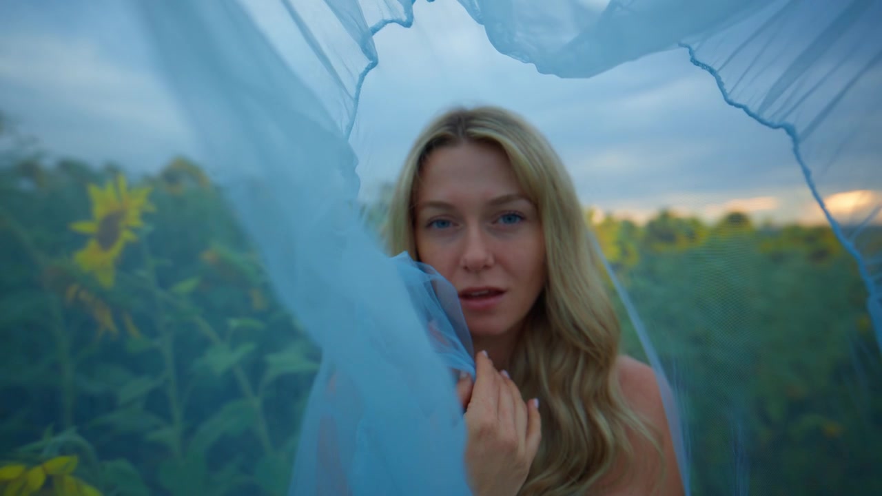 Giovane donna con velo blu in un campo di girasoli