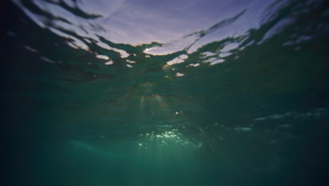 Weiße-Lichtstrahlen-Funkeln-Und-Leuchten,-Während-Sich-Meerwasser-über-Sand-Zu-Wellen-Aufbaut