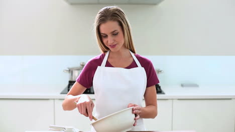 Smiling-blonde-woman-preparing-cake-in-kitchen