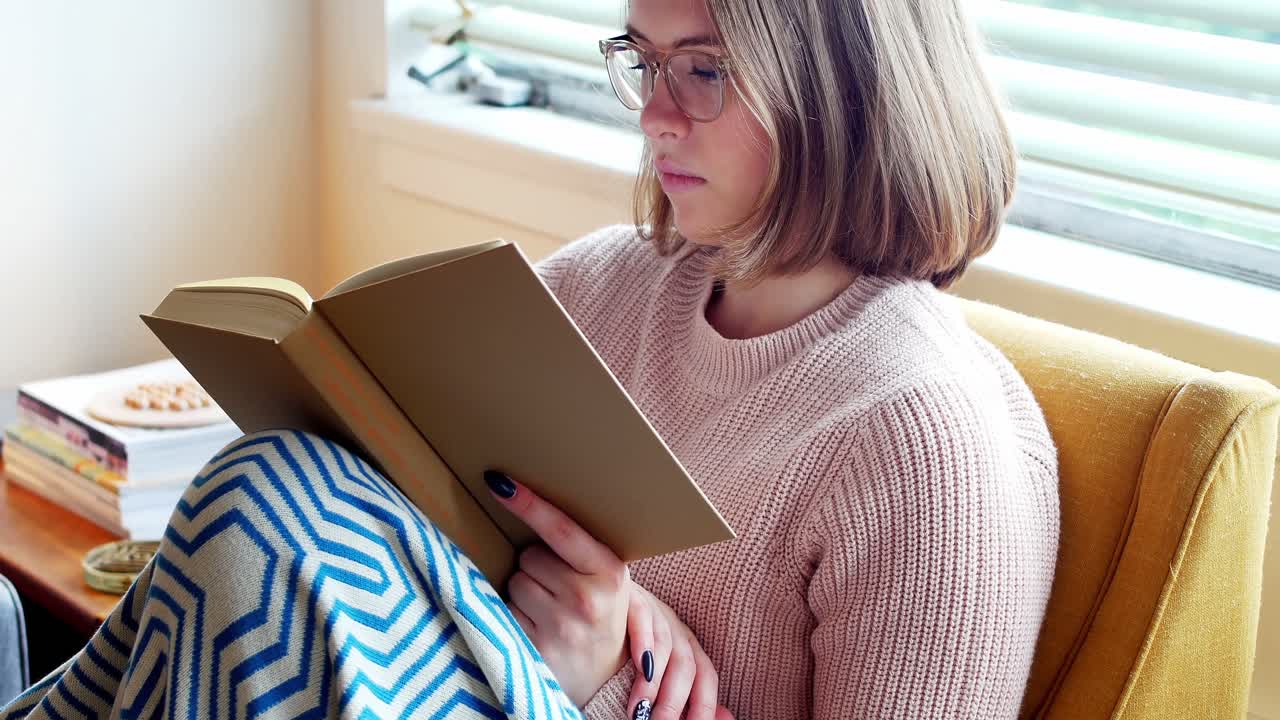 mujer leyendo una novela en la sala de estar