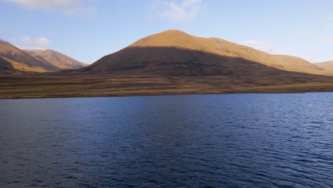 Drone-flying-above-Lake-Camp-while-sun-rises-and-hits-the-tips-of-mountains-with-golden-light