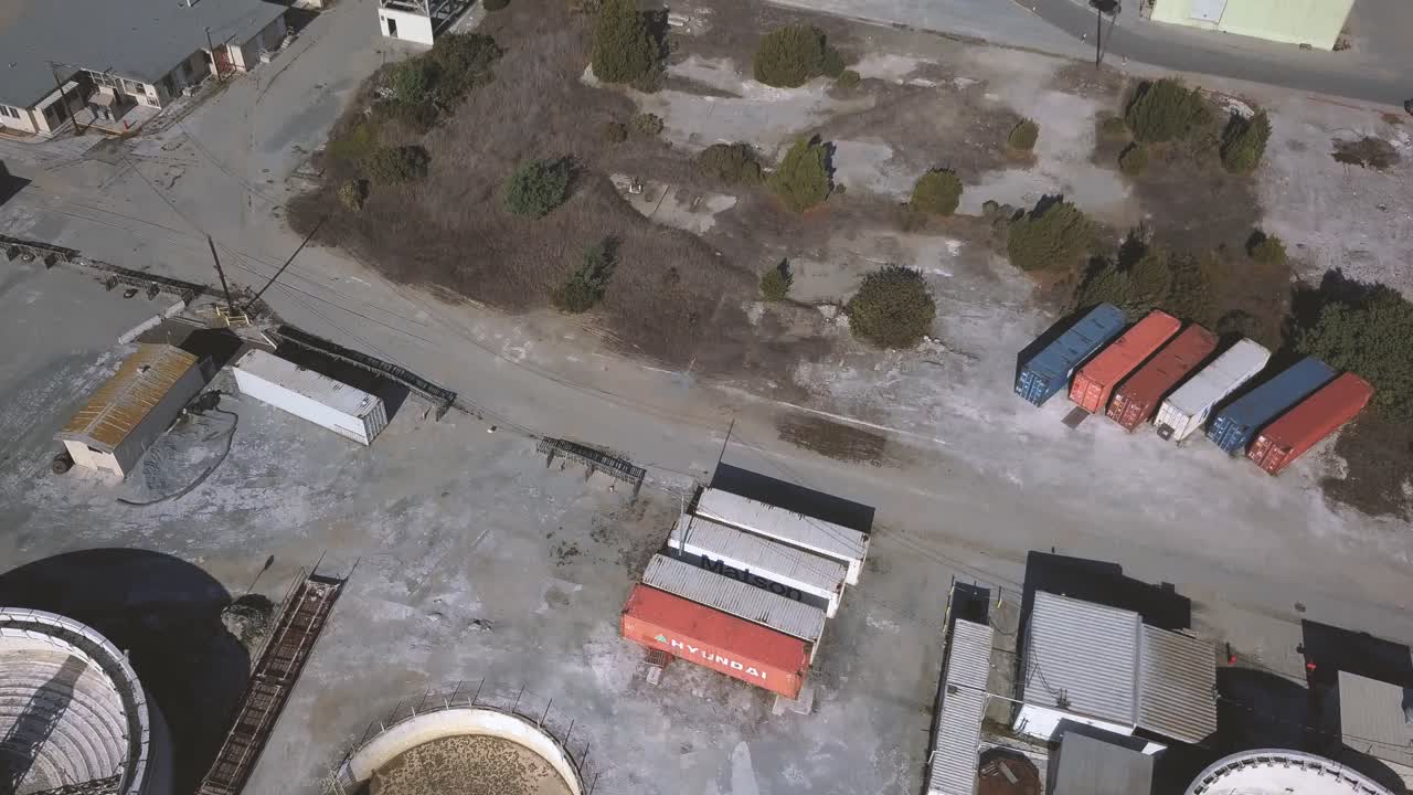 Moss Landing - California, USA. Cinematic aerial flyover of industry and shipping containers with pan up to reveal marina and shoreline energy facility. Filmed on DJI Mavic Pro