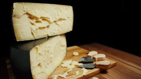 medium hard cheese head parmesan on wooden board, with cheese parmesan knifes. slide shot