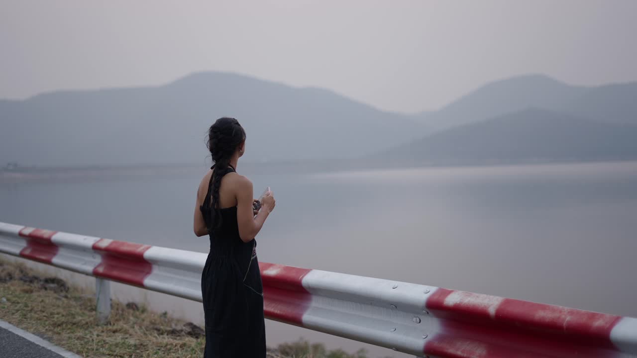 Woman by a Lake and Mountains Using Phone and Enjoying the View