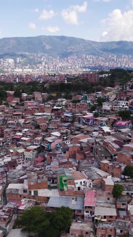 urban sprawl and colorful houses characterize comuna 13, also known as san javier, in medellin, colombia, as seen from an aerial perspective. vertical video
