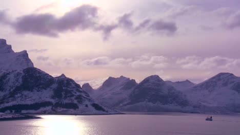 A-fishing-boat-heads-out-to-sea-in-golden-light-in-the-Arctic-Lofoten-Islands-Norway