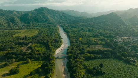 Aerial-view-flying-over-the-mountains-and-sea,-there-is-a-bridge-in-the-back,-Colombia,-mendihuaca,-la-guajira