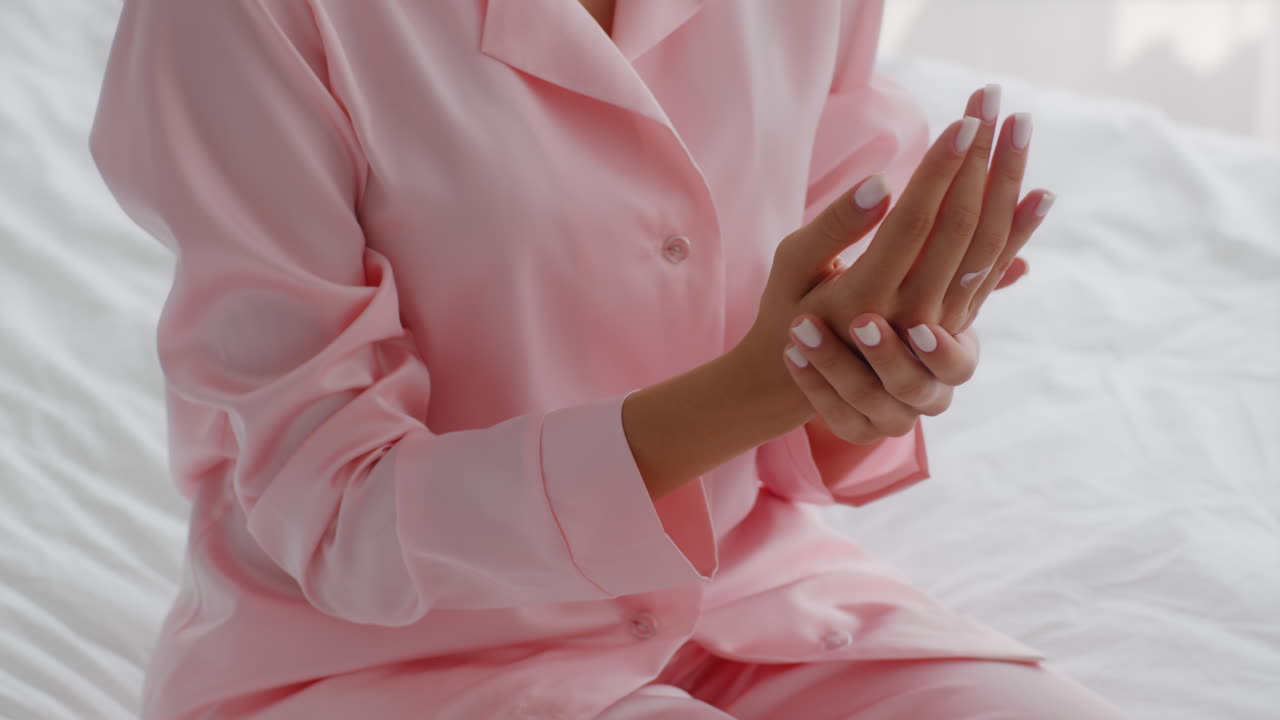 mujer en pijama rosa aplicando loción