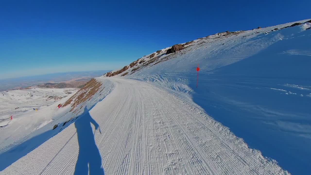 4K immersive POV skiing down "El Águila" red slope in Sierra Nevada, Spain, featuring high-speed carving on a groomed trail with mountain views under a clear blue sky