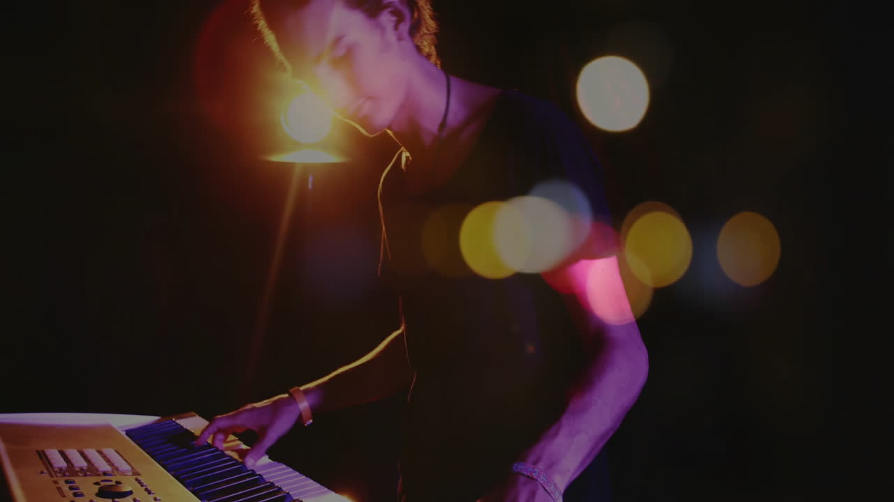 Mandlig musiker spiller keyboard på musikklubscene, med svævende animerede bokeh-lys