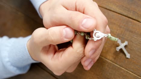 praying hands holding rosary