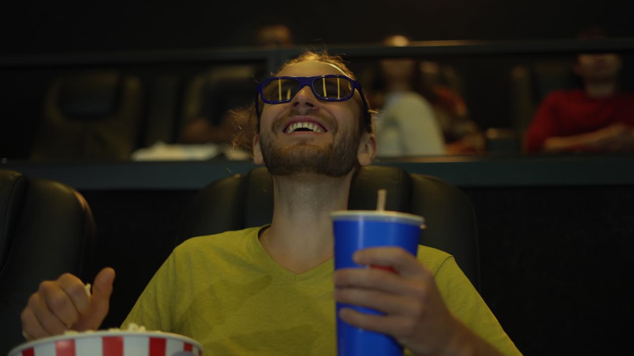 A man in 3d glasses watching comedy movie at the cinema and taking popcorn