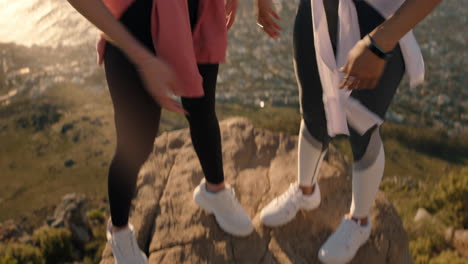 funny girl friends dancing on mountain top celebrating successful hiking adventure with victory dance