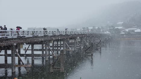 arashiyama in kyoto, snow flakes falling over togetsukyo bridge