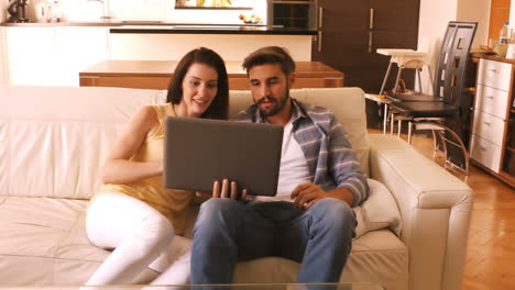 pareja relajándose en el sofá y usando la computadora portátil
