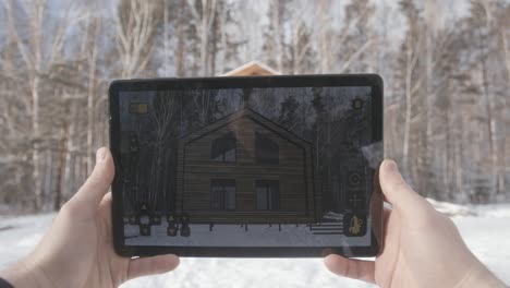 wooden house in winter forest viewed on a tablet