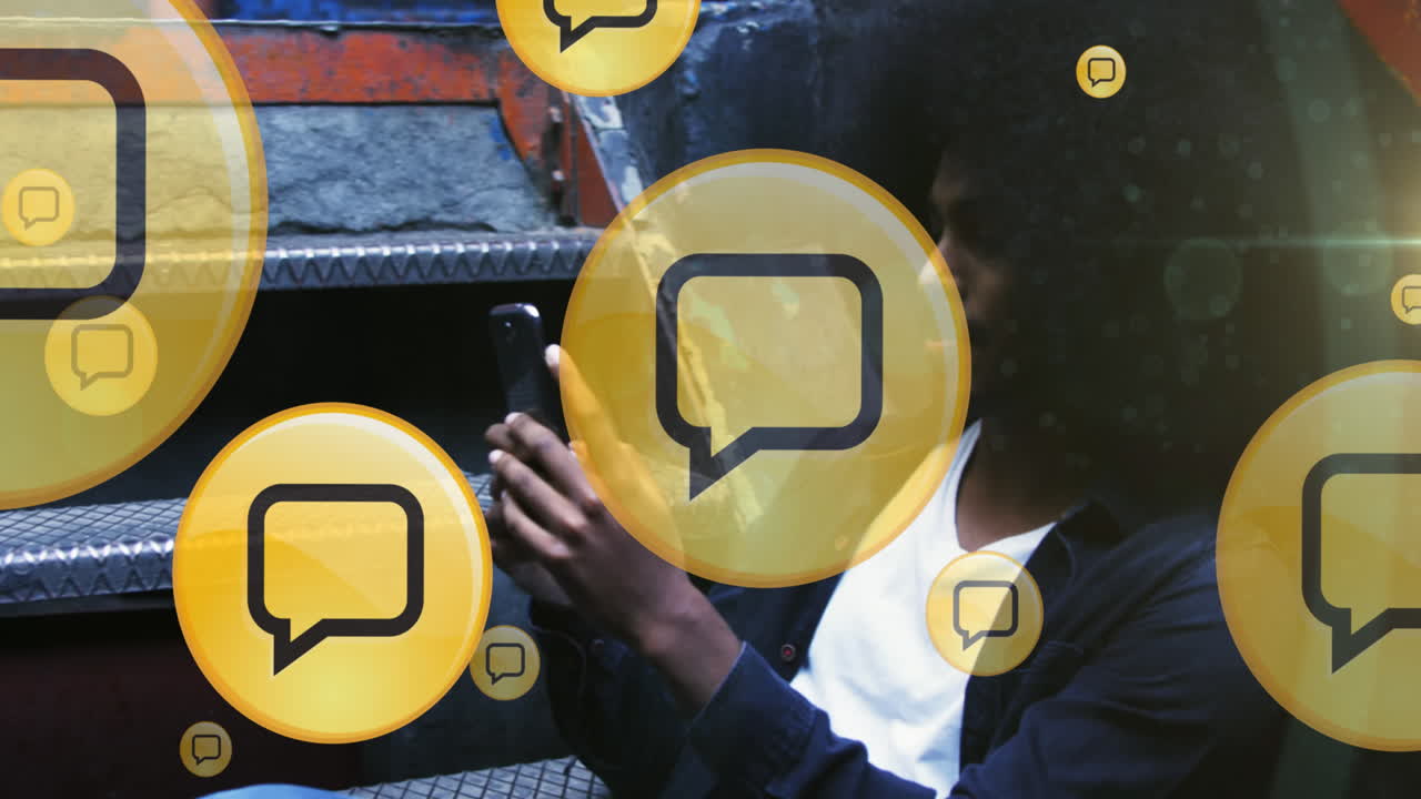 múltiples iconos de mensajes flotando contra un hombre afroamericano usando un teléfono inteligente sentado en las escaleras