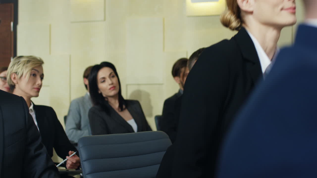회의실에 있는 사람들 사이에 빈 의자에 앉아 있는 백인 젊은 여성 사업가