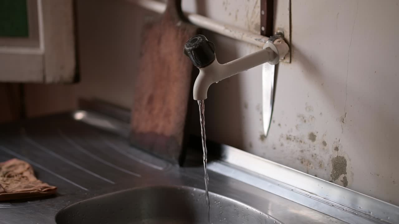 Water dripping from a faucet, slow-motion shot, rustic kitchen setting, Manaus, Brazil