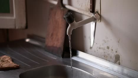 water dripping from a faucet, slow-motion shot, rustic kitchen setting, manaus, brazil