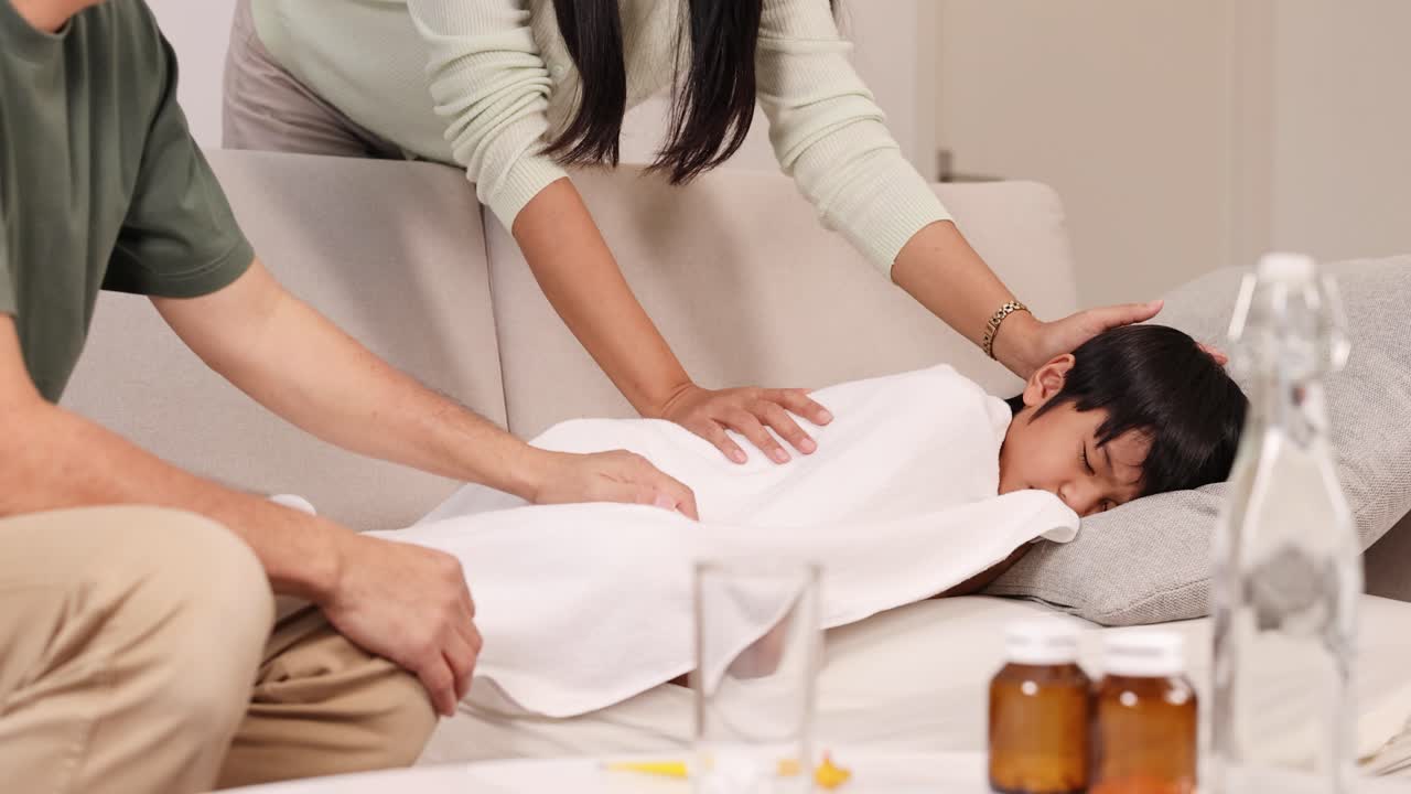Parents care for their sick son on a couch in a warm, cozy home
