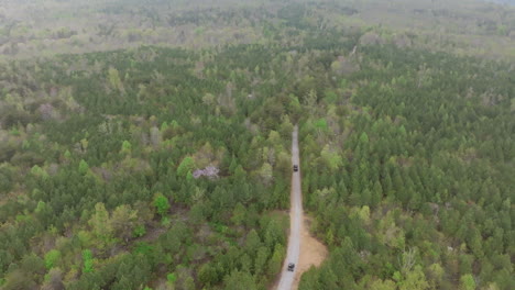 static aerial footage of two vehicles slowly following driving on a dirt road in the sequatchie valley in east tennessee