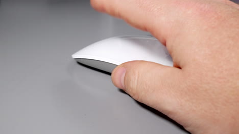 man using a white computer mouse on grey table desk