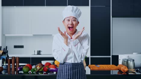 asian woman chef smiling and saying wow in home kitchen