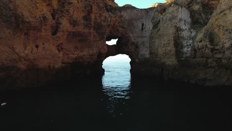 fly through rocky arch, on a sunny morning in algarve, portugal