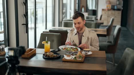 carismático bloguero adulto habla sobre comida en cámara en un restaurante