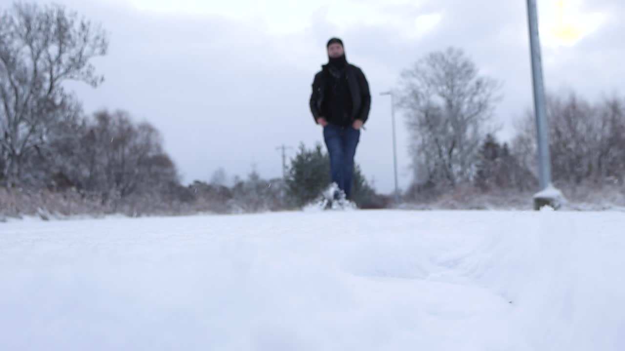 Person walking in thick white fluffy snow towards the camera or the viewer in slow motion making the snow fly around with movement. Person comes into camera focus while he reaches walks closer slowly.