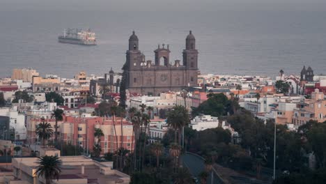 day to night timelapse of las palmas, featuring the cathedral of santa ana, colorful buildings, palm trees, and an ocean view with a passing ship. ideal for tourism, urban, and cultural projects.