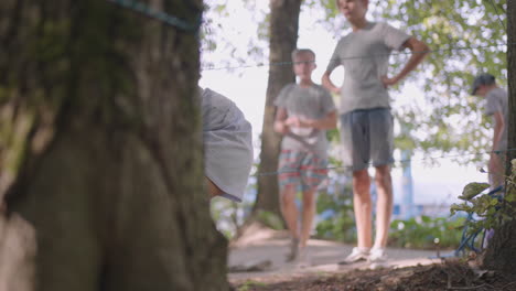 niños en un campamento de verano caminan por el suelo. entrenamiento para pasar obstáculos arrastrándose por el suelo. una niña cae en el bosque en una tarea de campamento