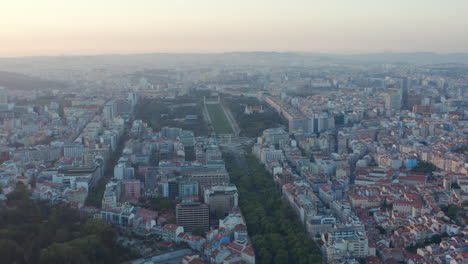 Wide-panoramic-side-slider-view-of-rooftops-of-residential-houses-in-Lisbon-city-center-with-large-lush-green-public-park