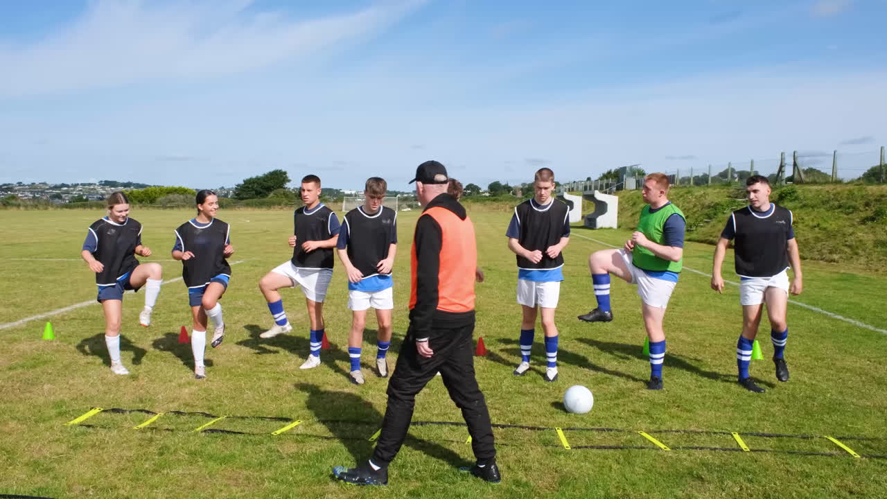 Soccer coach guiding team through agility drills on sunny field