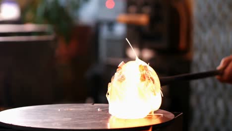 Glassblower-rolling-molten-glass-on-pieces-of-colored-glass