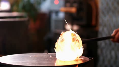 glassblower rolling molten glass on pieces of colored glass