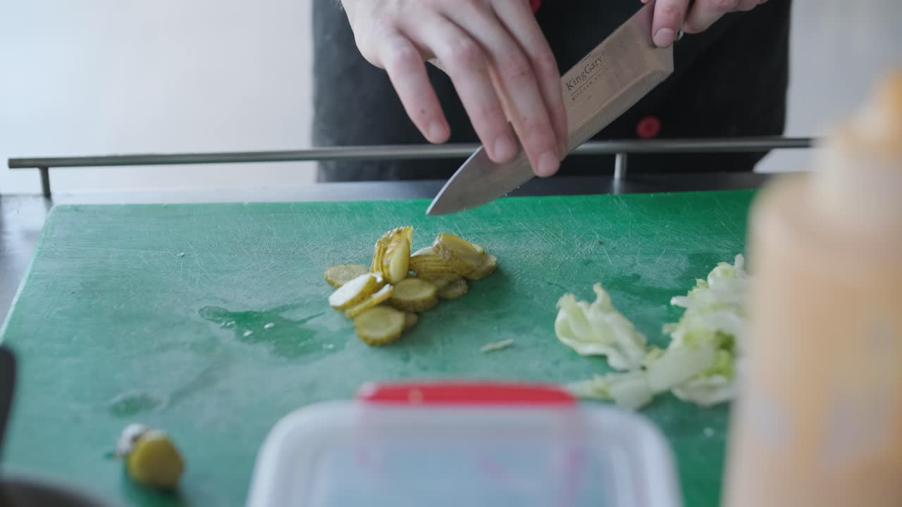 요리사 는 샌드위치 를 위해 피클 과 러드 를 준비 하고 있다