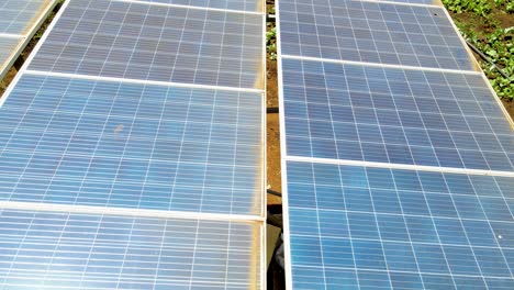 aerial drone view into large solar panels at a solar farm at bright sunset