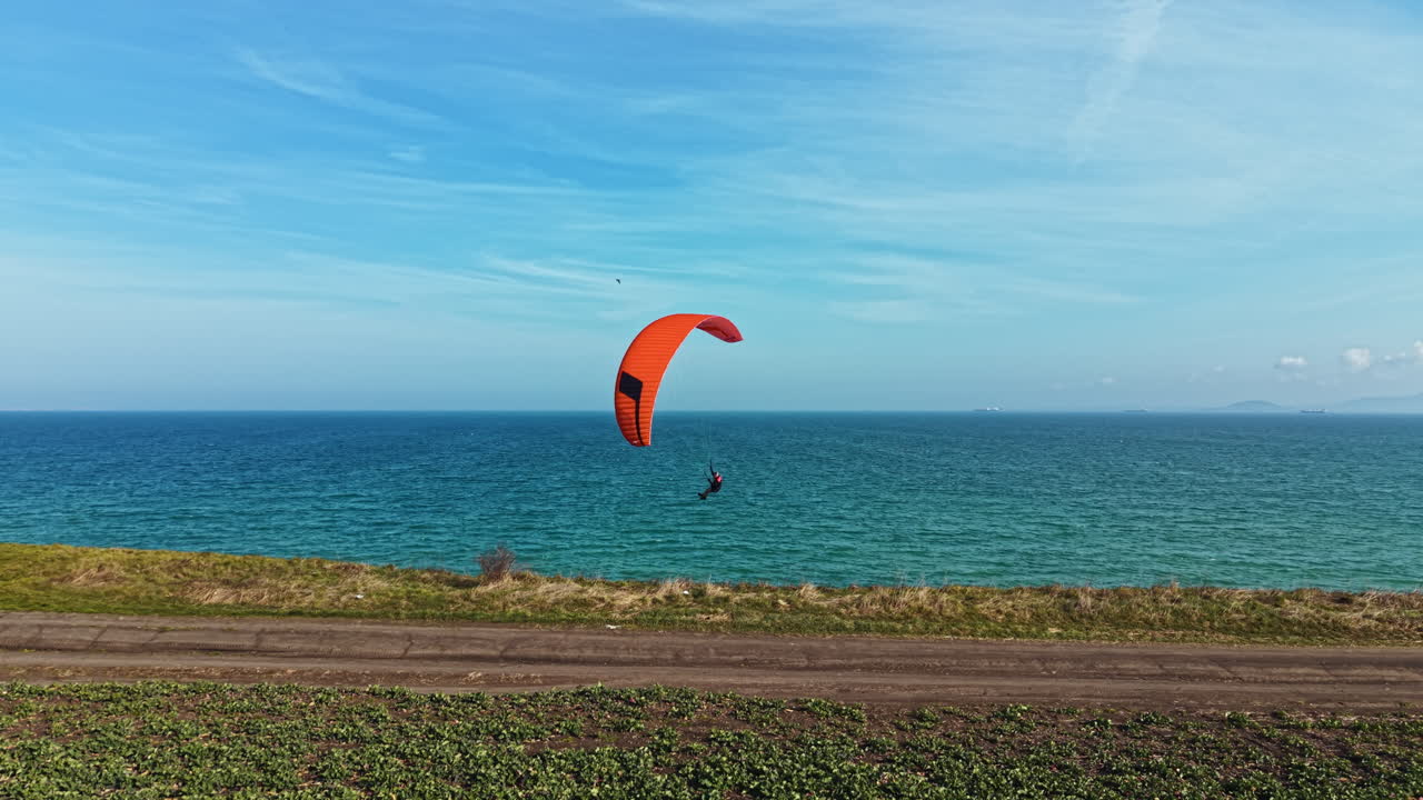 Parapente sobre el agua cerca de la costa con tiempo despejado y un cielo azul lleno de nubes ligeras
