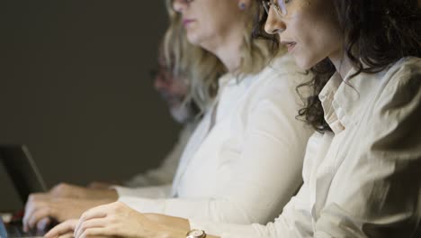 focused business colleagues using computers in dark office