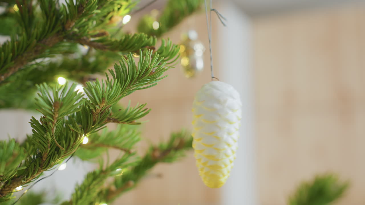 Close view of elegant ornament hanging on Christmas tree surrounded by glowing fairy lights, vibrant green pine branches, warm festive indoor setting creating cozy joyful holiday atmosphere