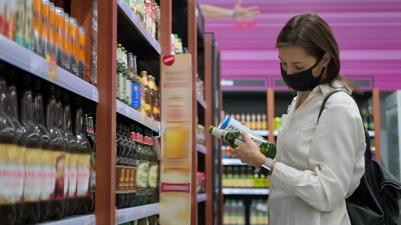 한 여자 가 식료품 가게 에서 술 을 구입 하고 있다